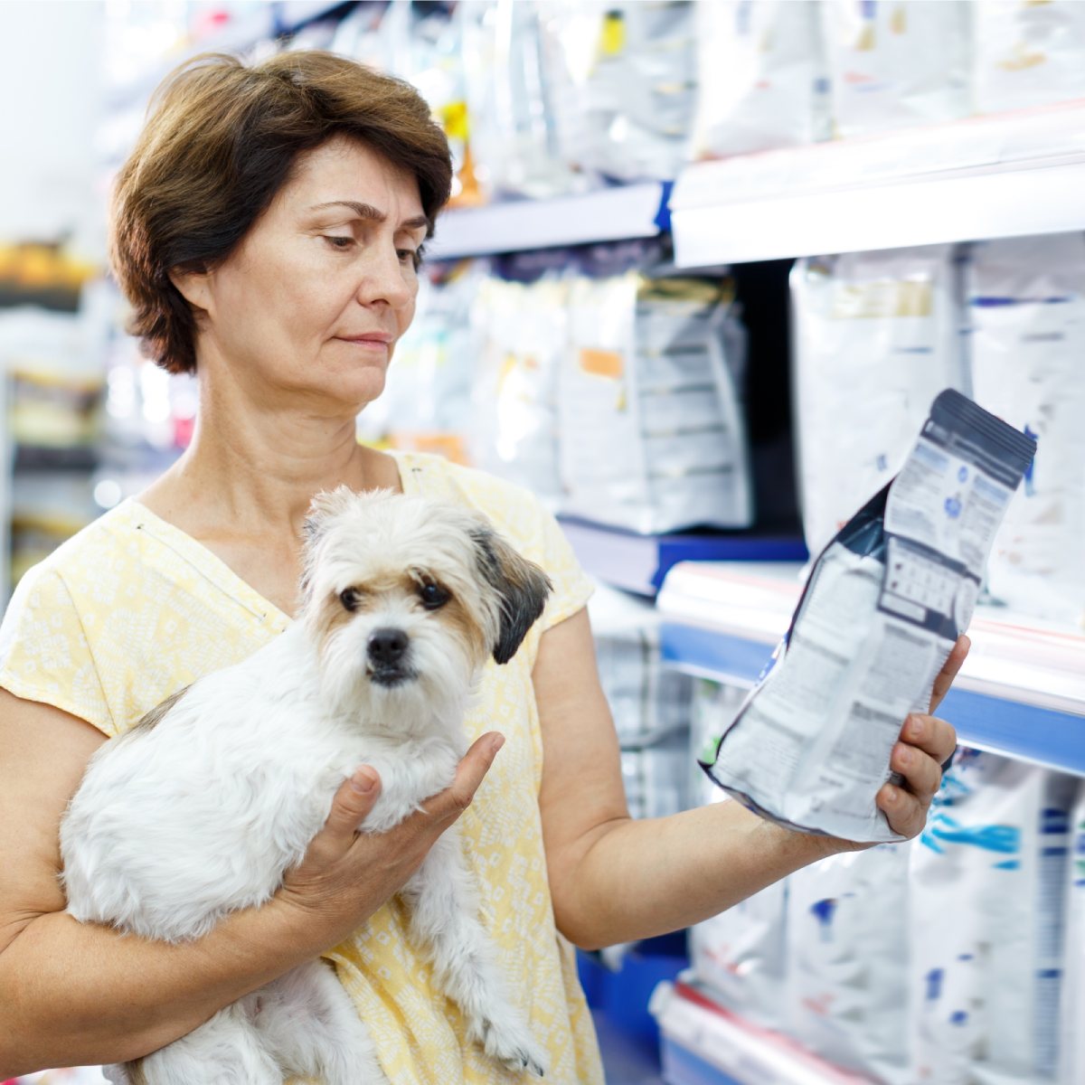 Glad woman choosing dog food for her puppy (1)